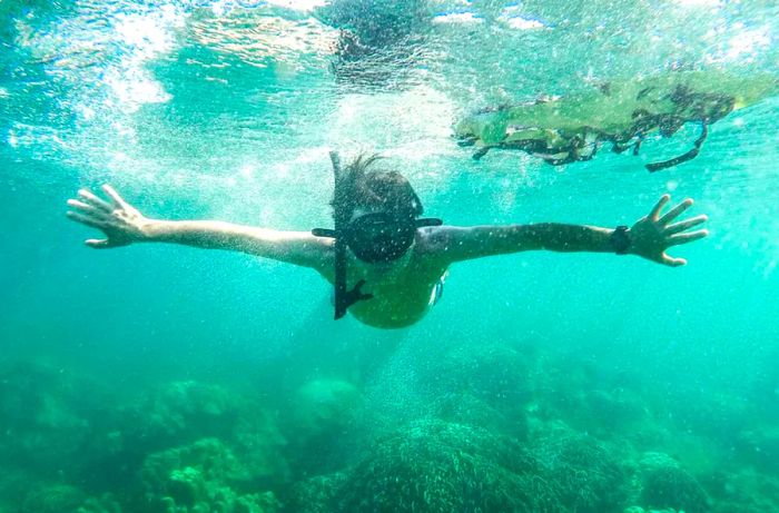 Asian tourists engaging in diving to explore stunning coral reefs.