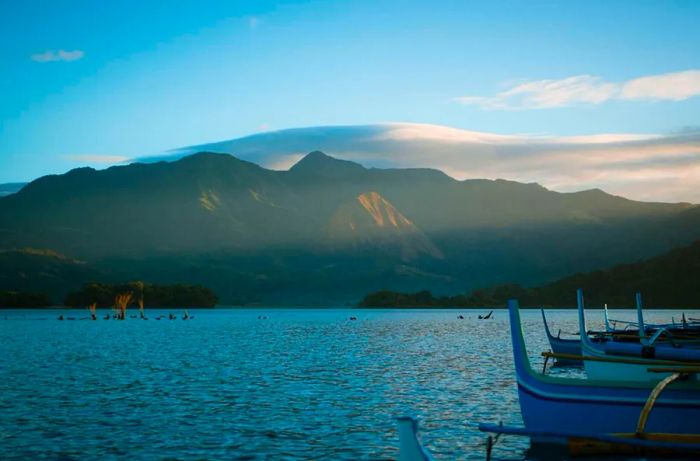 Couples enjoying a camping experience at Lake Mapanuepe during morning and sunset, with a picturesque mountain backdrop.