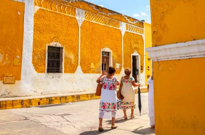 Two women stroll through a vibrant corner in Merida, Mexico