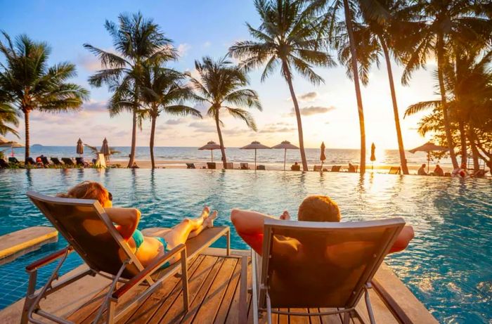 couple enjoying the beach by the luxurious swimming pool, luxury travel