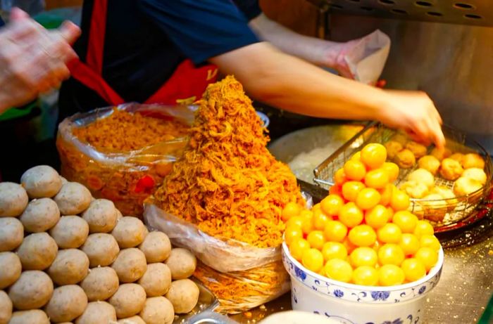 At Ningxia Night Market in Taipei, a vendor offers Deep-Fried Taro Balls, which are small taro balls filled with salted egg yolk. This beloved Taiwanese dessert is a favorite among both locals and visitors.