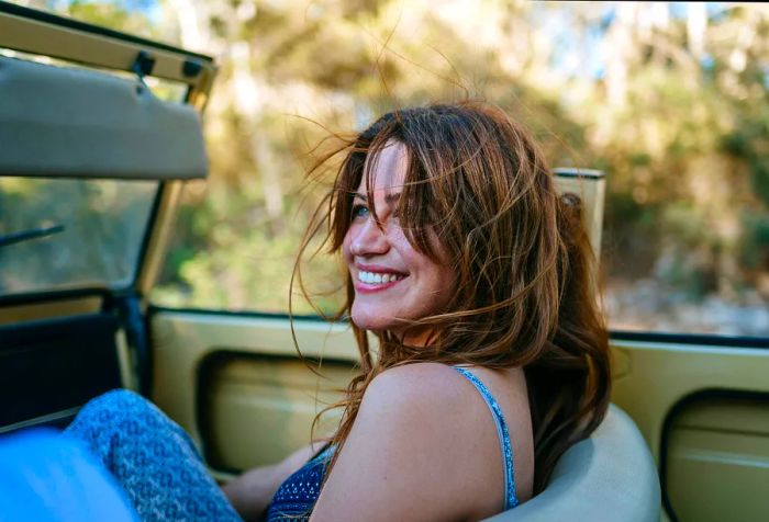 A cheerful woman enjoying the ride in a convertible with the top down.