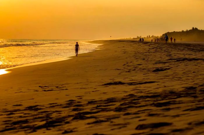 A figure strolls along the beach at sunset in Zipolite, Mexico.