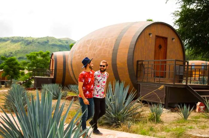 A couple strolls past a wine-barrel-shaped hotel suite in Tequila, Mexico.