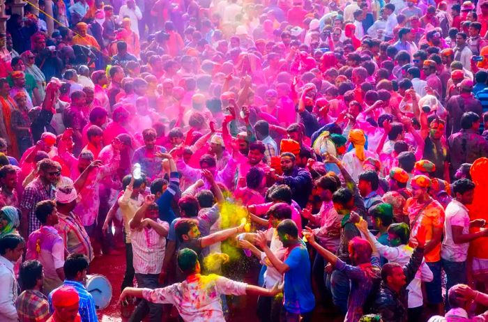 A vibrant gathering of Hindu devotees celebrating Holi with colorful powders at a temple in Nandgaon near Mathura, Uttar Pradesh, India.