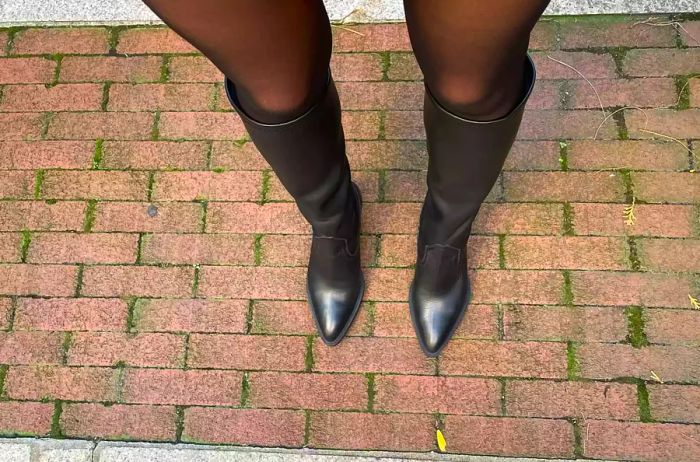 A person dons a pair of La Canadienne Paton Leather Boots outdoors