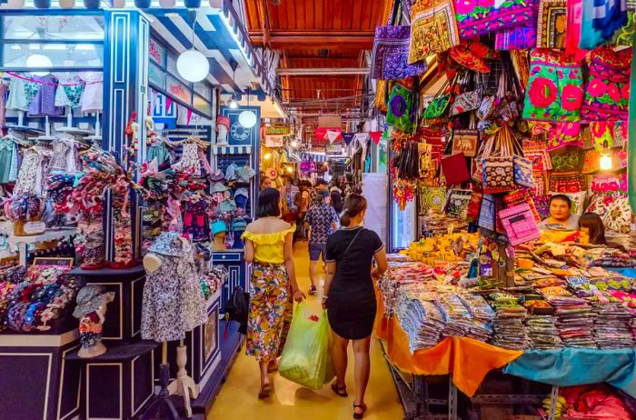 Two women stroll through the aisles of a market in Bangkok, Thailand