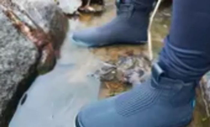 A person stands in a puddle while donning Vessi Weekend Waterproof Chelsea Boots