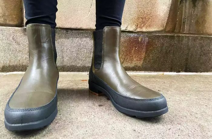 A person sporting Forsake Sofia Chelsea Women's Waterproof Outdoor Boots while walking on a sidewalk