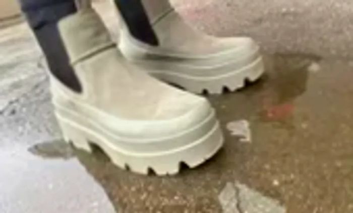 A person stands in a puddle wearing UGG Brisbane Waterproof Chelsea Boots