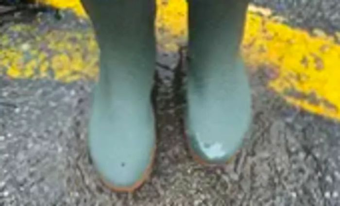 Close-up of feet in Bogs Women's Sweetpea Tall Rain Boots standing in the rain