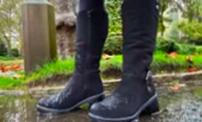 A person is seen wearing Overland Women's Major Shearling-Lined Waterproof Suede Boots outdoors in the rain