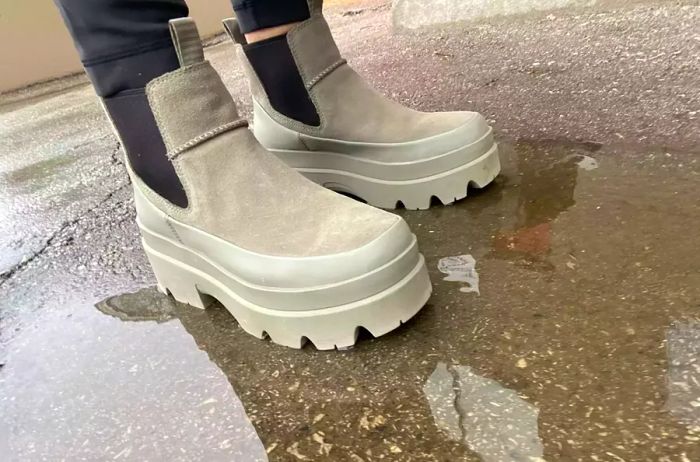 A person steps into a puddle while wearing UGG Brisbane Waterproof Chelsea Boots