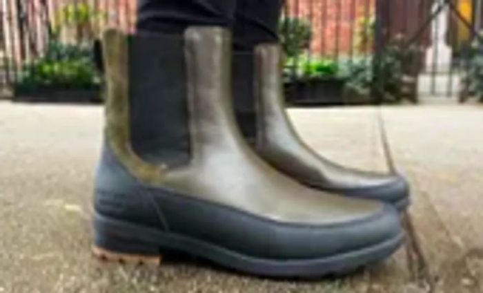 A person walks on a sidewalk wearing Forsake Sofia Chelsea Women's Waterproof Outdoor Boots