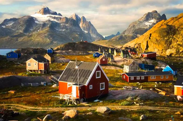 A vibrant fishing village in Greenland set against a backdrop of snowy mountains