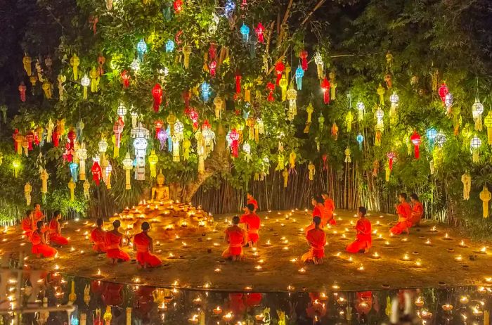 Vibrantly colored lanterns suspended in a tree above monks in orange robes