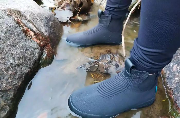 A person is standing in a puddle while sporting Vessi Weekend Waterproof Chelsea Boots