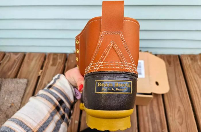 A hand grips a L.L. Bean Women's 6-Inch Bean Boot