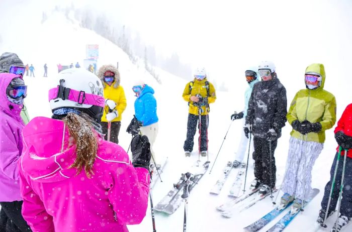 A group of skiers gathers together on a snowy mountain.