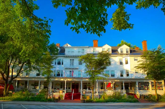 A picturesque, tree-lined road featuring the charming exterior of The Red Lion Inn in the Berkshires