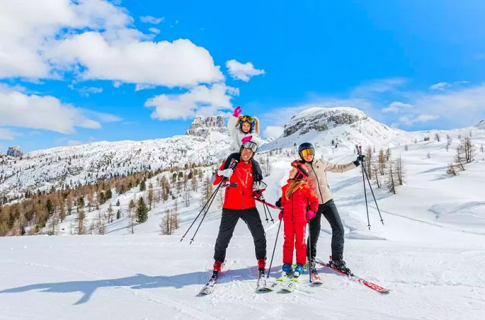 A family stands together in ski gear on a picturesque snowy mountain