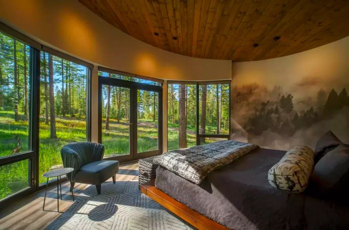 A villa bedroom featuring expansive windows overlooking the forest