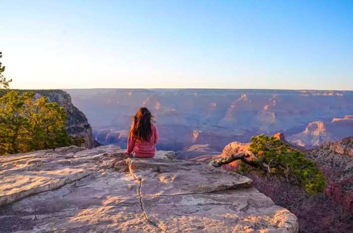 A woman perched on a cliff at the Grand Canyon