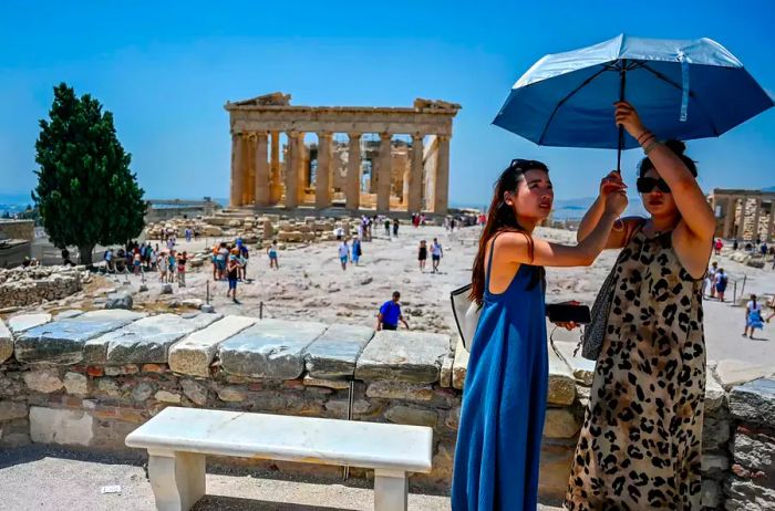 Two women protect themselves from the intense sun at the Acropolis