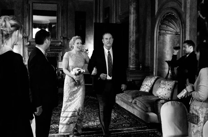 The bride walks down the aisle alongside an older gentleman during the wedding ceremony.