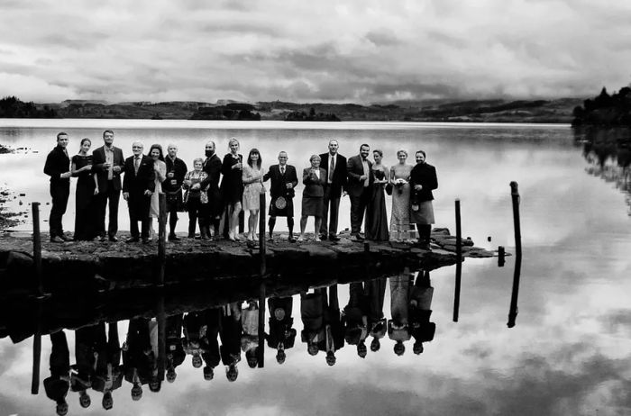 Wedding guests gather by the water for a group photo following the ceremony.