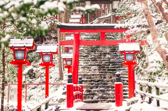 A red archway adorned with lights, all blanketed in snow