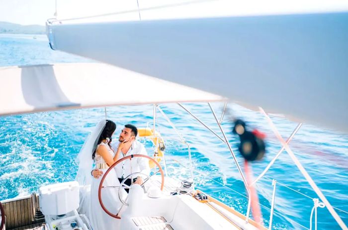 A couple embraces at the helm of a yacht sailing on the ocean.