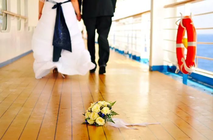 Wedding couple strolling on the deck of a cruise ship, holding a bouquet