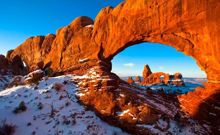 Utah arch during golden hour with snow covering the ground