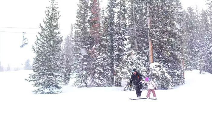 A parent and child enjoying snowboarding at Brighton Resort in Colorado.