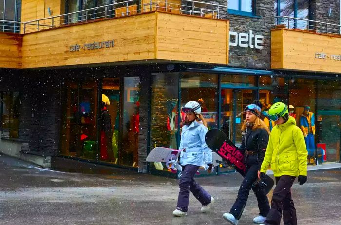 Groups of people strolling through town while carrying their snowboards.