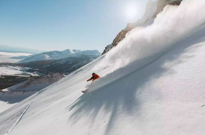 A snowboarder carving down a steep slope on Mammoth Mountain