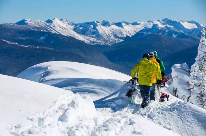 A group of individuals carrying snowboards across snowy mountains.