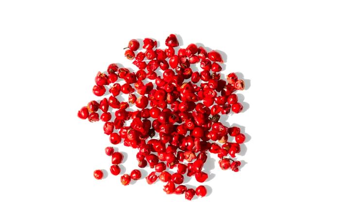 A collection of pink peppercorns from Spicewalla, displayed on a white background