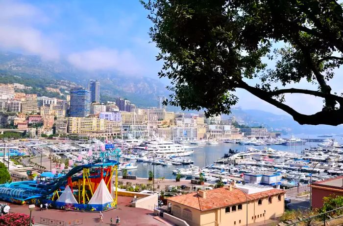 Aerial view of Monte Carlo harbor in Monaco, featuring Port Hercules filled with yachts and water slides at the port along with an outdoor aquapark.