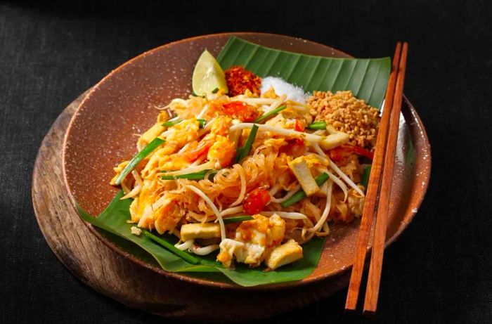 Pad Thai is a beloved street food dish, representing authentic Thai cuisine against a dark backdrop with ample space for text.