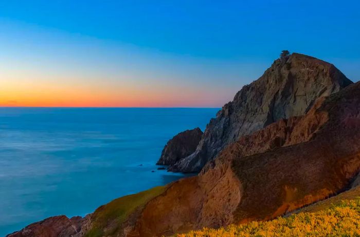 Rugged coastal cliffs along the Devil's Slide trail in California during sunset, with a silky ocean captured through long exposure