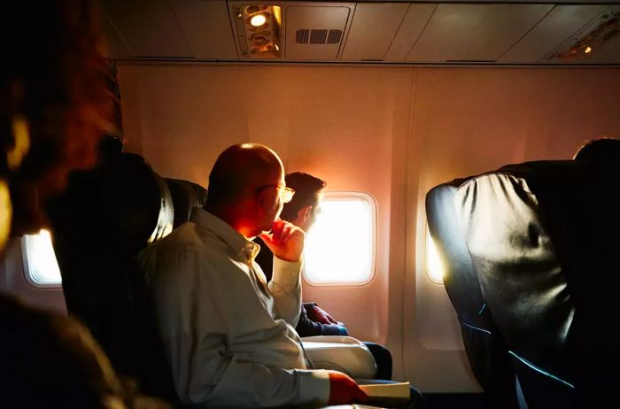 Business professionals aboard a flight, gazing at the sunset through the airplane window.