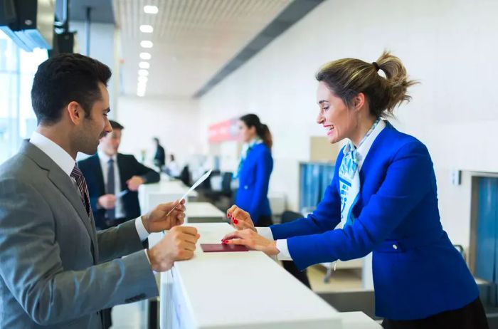 A businessman at the check-in counter holding his boarding pass.