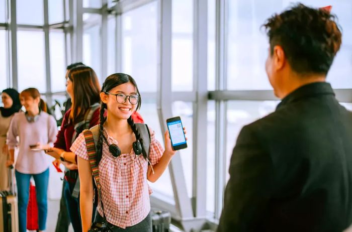 Young girl checking in at the airport on her phone