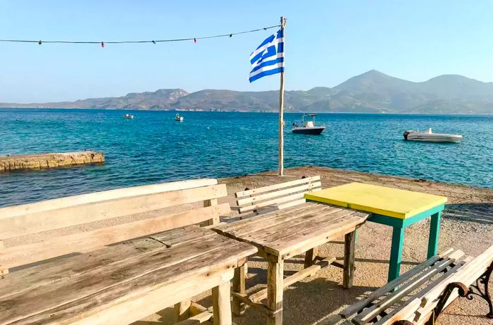 A Greek flag waves on a small dock in Milos.