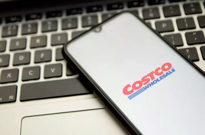 The Costco logo displayed on a smartphone with a computer keyboard in the background in Athens