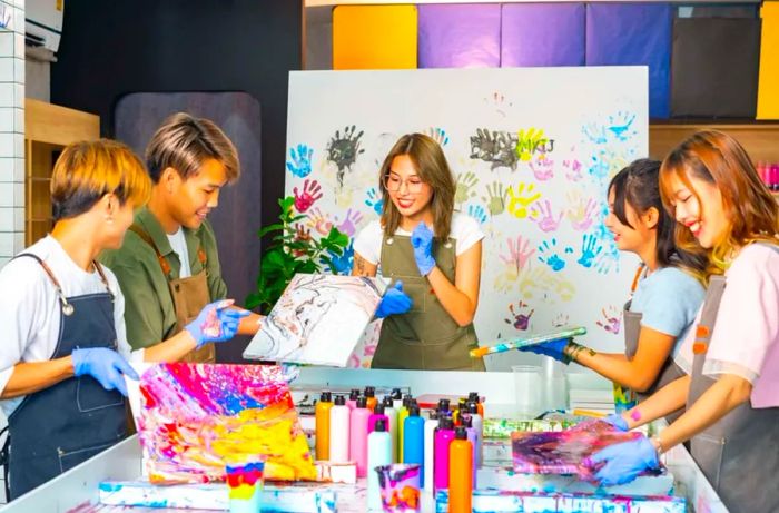 A group of Generation Z individuals from Asia engaging in an acrylic pouring art workshop at an art studio.