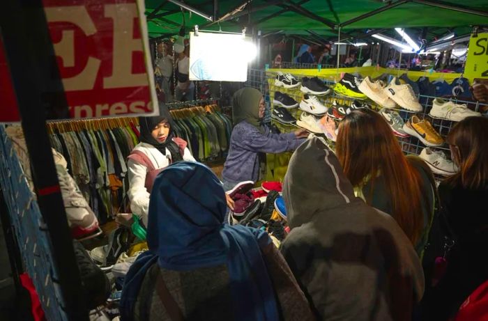 At the Night Market along Harrison Road, a vendor offers shoes and clothing at an ukay-ukay stall.