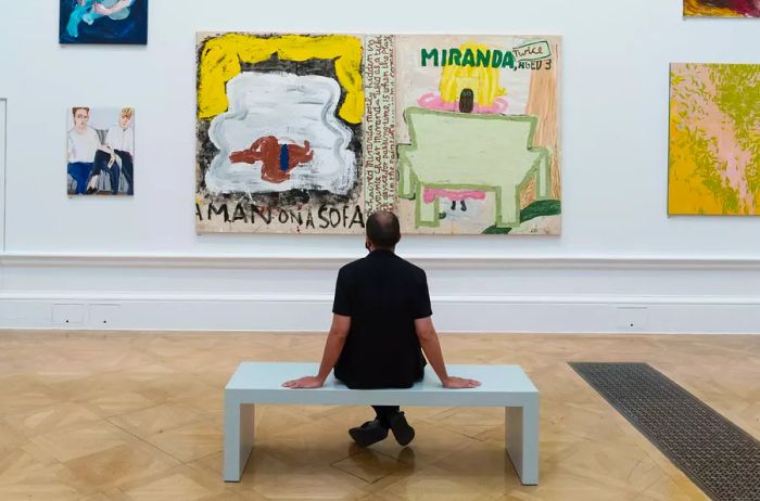 A gallery staff member examines 'Miranda, Twice and Caliban' by Rose Wylie during a preview of the 253rd Summer Exhibition at the Royal Academy of Arts.